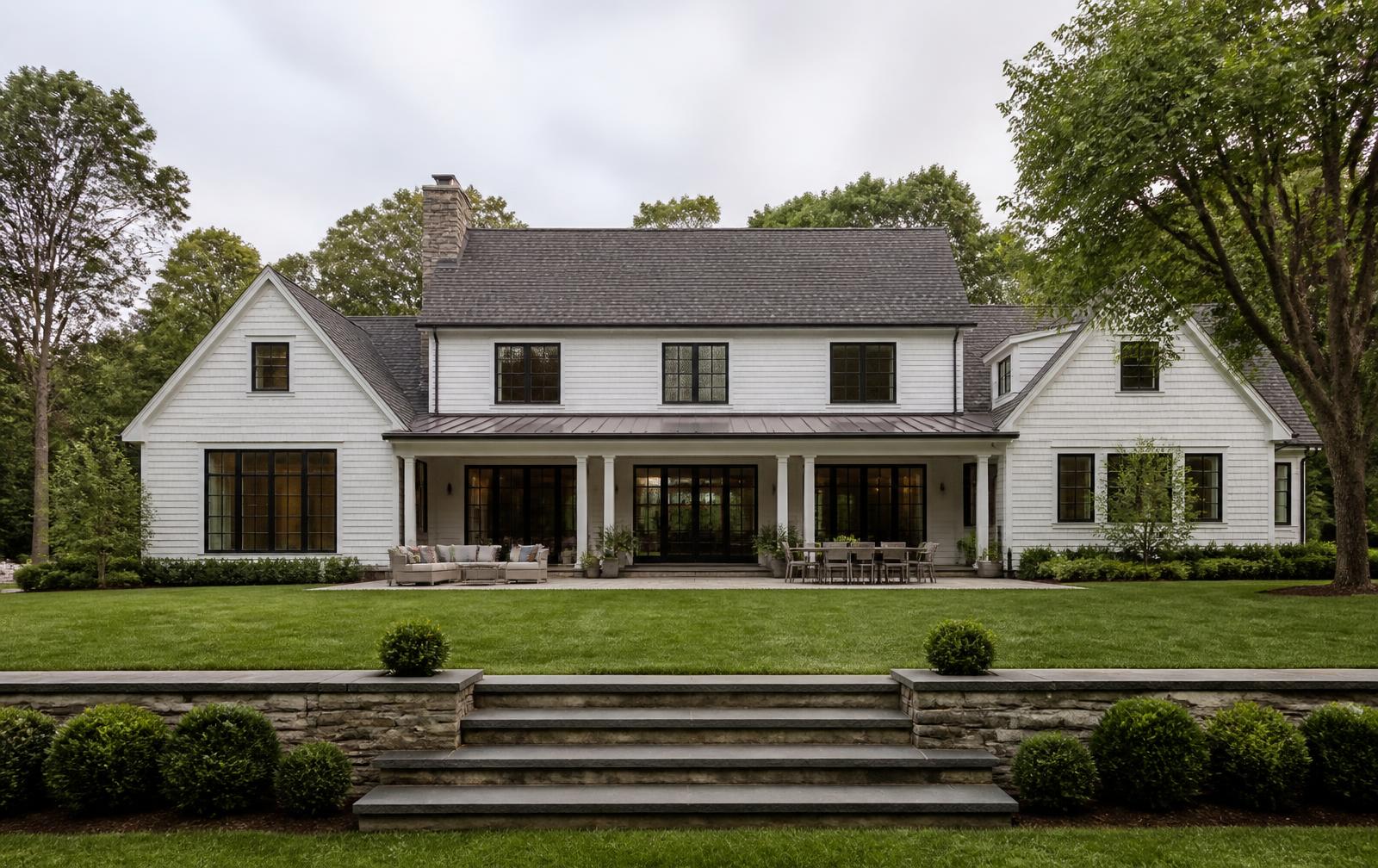 Concept visualization of the garden elevation of a white shingled estate with a deep covered porch, bluestone terrace and clipped hedges