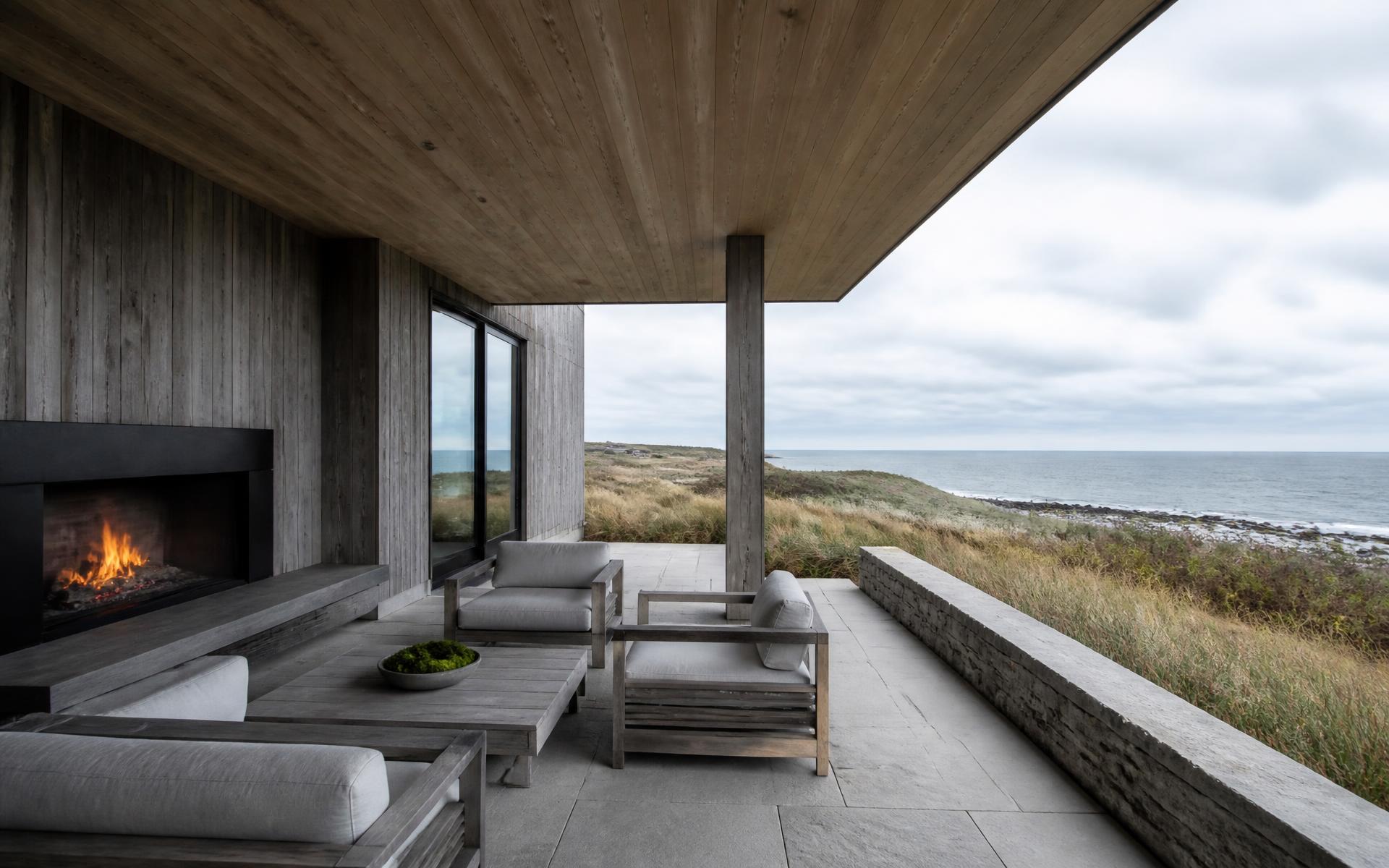 Concept visualization of a covered outdoor living area with white oak soffit, granite paving and a blackened metal fireplace facing the ocean