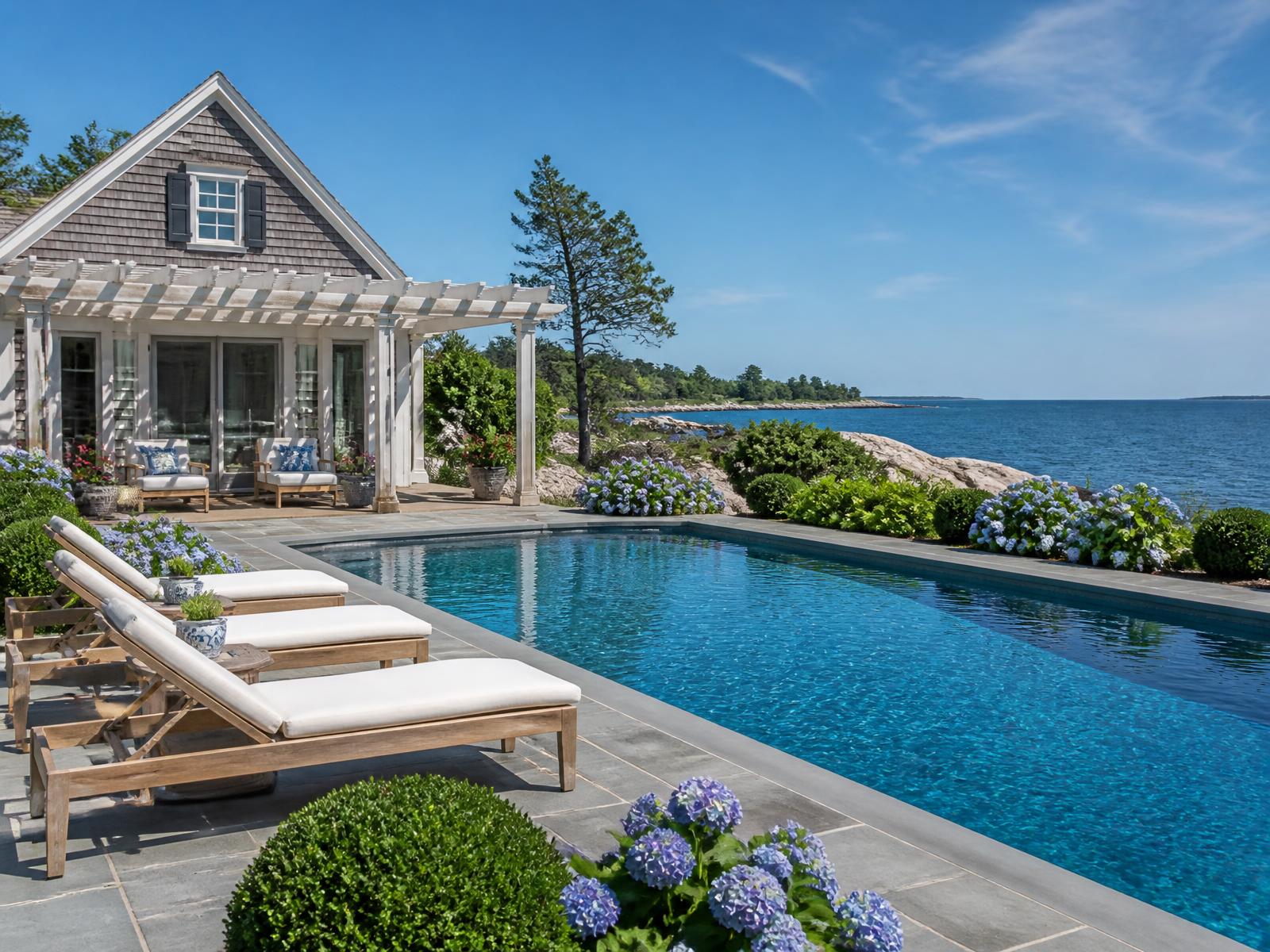 Gunite pool and shingled pool house with pergola above the Maine coastline