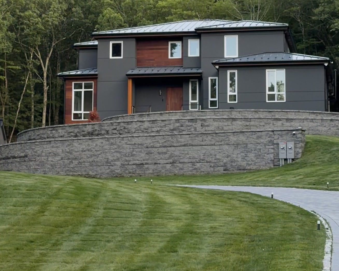 Bedford Residence — front elevation with cedar accents, standing-seam roof and curved stone retaining wall