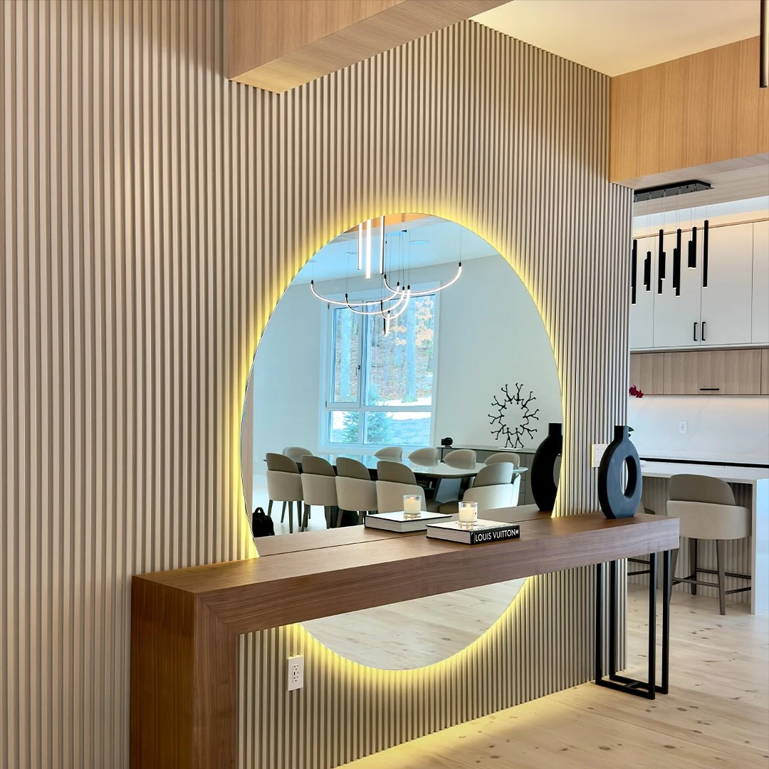 Backlit arched mirror and walnut console at the Bedford Residence reflecting the dining room beyond