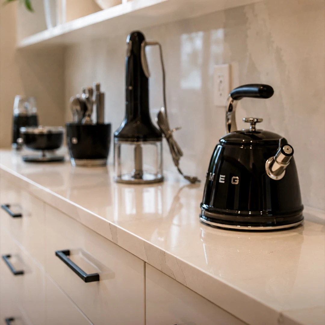 Close detail of the pantry counter at the Bedford Residence showing stone edge, blackened pulls and small appliances