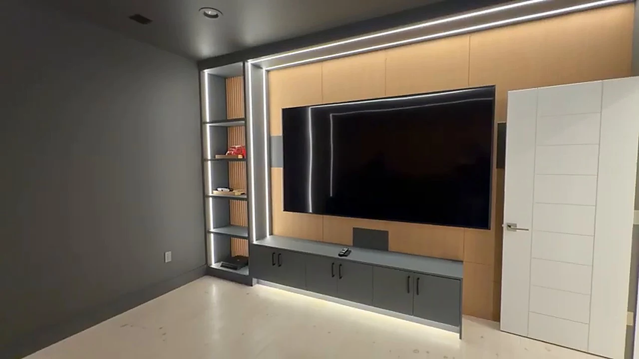 Lower-level media wall at the Bedford Residence in white oak panelling with an LED reveal frame and a run of slab-front cabinetry