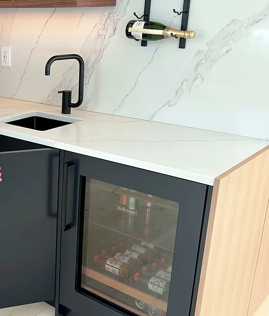 Wet bar detail at the Bedford Residence with a marble slab counter, blackened tap, wine refrigeration and wall-mounted bottle storage